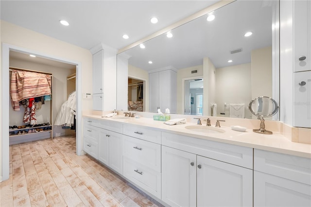 8592 Hidden Lagoon Rd, Sarasota, FL 34242 - bathroom with a walk in closet, double vanity, wood finished floors, and recessed lighting