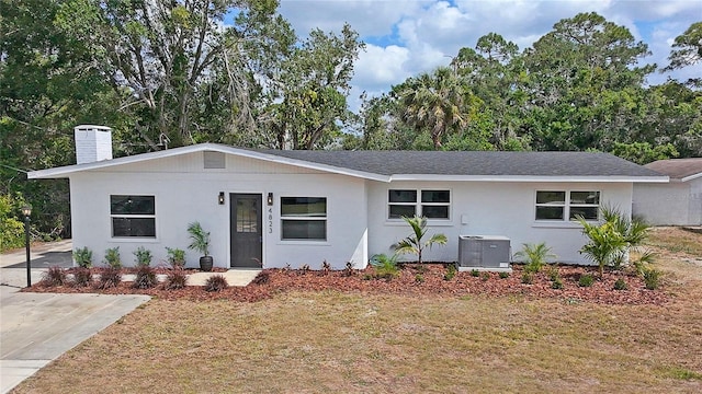 single story home with a chimney, cooling unit, and stucco siding