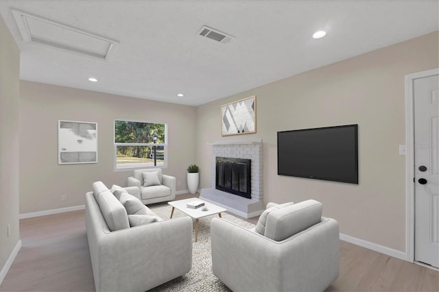 living area featuring attic access, visible vents, baseboards, light wood-style floors, and recessed lighting
