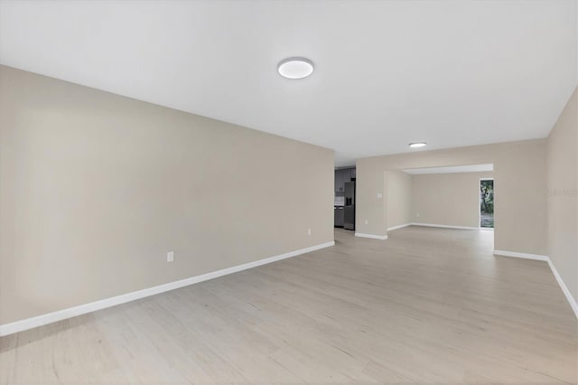 spare room with baseboards and light wood finished floors