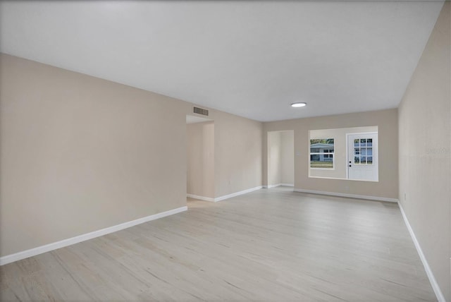 unfurnished room with baseboards, light wood-style flooring, and visible vents