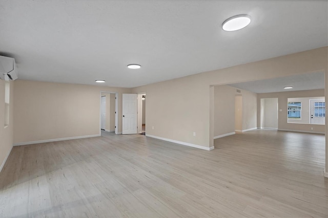 interior space featuring baseboards, an AC wall unit, and light wood-type flooring
