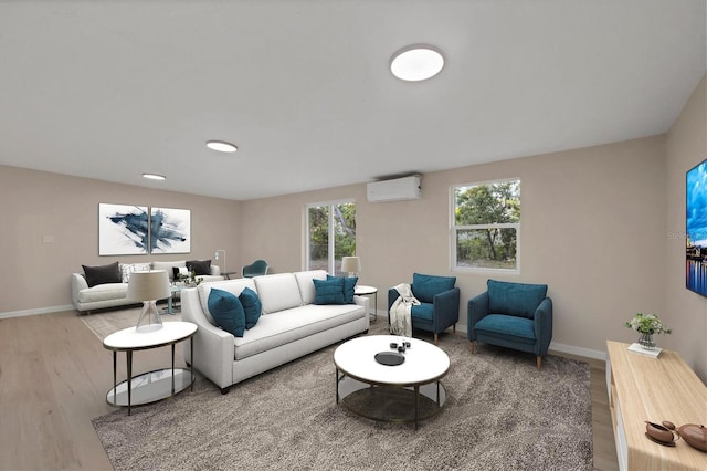 living room with baseboards, a wall unit AC, and wood finished floors