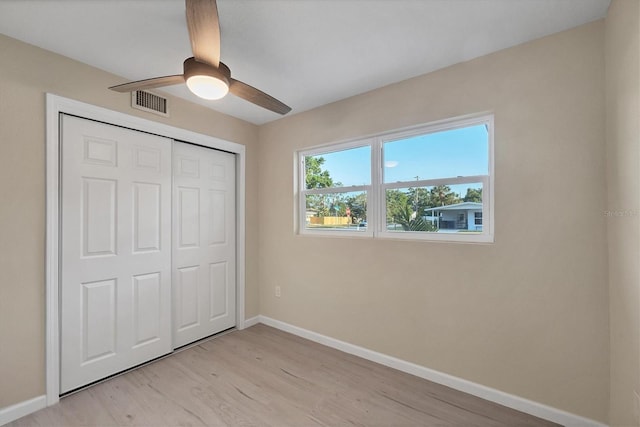 unfurnished bedroom featuring ceiling fan, visible vents, baseboards, a closet, and light wood-style floors