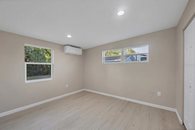 unfurnished room with baseboards, light wood-style flooring, recessed lighting, and a wall mounted air conditioner