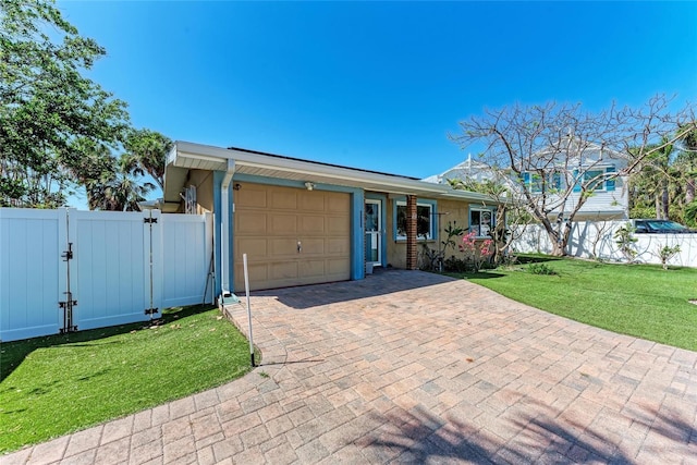 view of front facade with a gate, decorative driveway, a front lawn, a garage, and fence