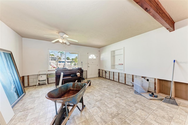 interior space with stone finish flooring, beam ceiling, and ceiling fan