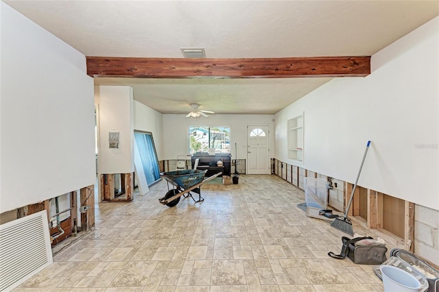 living area featuring stone finish flooring, beamed ceiling, ceiling fan, and visible vents