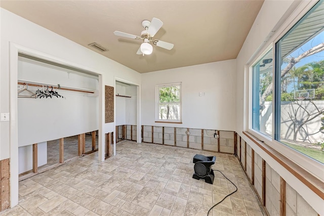 unfurnished bedroom with visible vents, multiple closets, and a ceiling fan