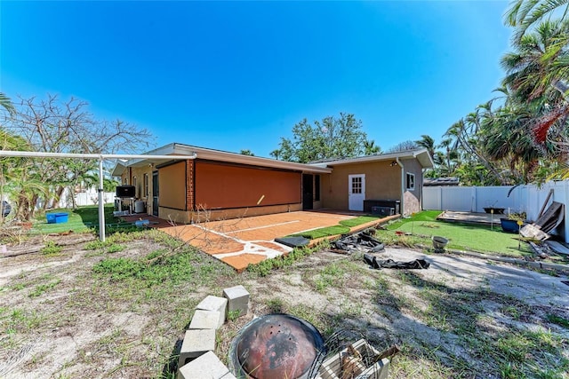 rear view of house featuring a patio area, stucco siding, fence, and a yard