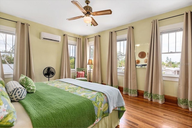 2326 2nd Ave E, Bradenton, FL 34208 - bedroom featuring multiple windows, an AC wall unit, wood finished floors, and baseboards