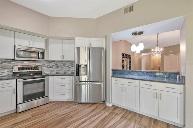 1712 Starling Dr Unit 101, Sarasota, FL 34231 - kitchen featuring appliances with stainless steel finishes, tasteful backsplash, white cabinetry, and visible vents