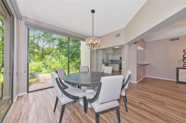 1712 Starling Dr Unit 101, Sarasota, FL 34231 - dining area featuring an inviting chandelier, baseboards, wood finished floors, and visible vents