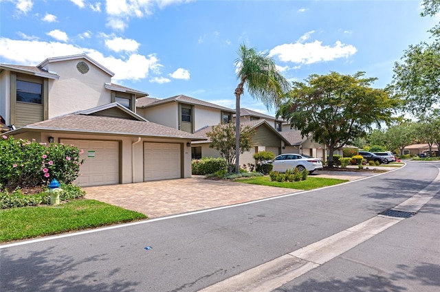 1712 Starling Dr Unit 101, Sarasota, FL 34231 - view of property featuring driveway, roof with shingles, a residential view, an attached garage, and stucco siding