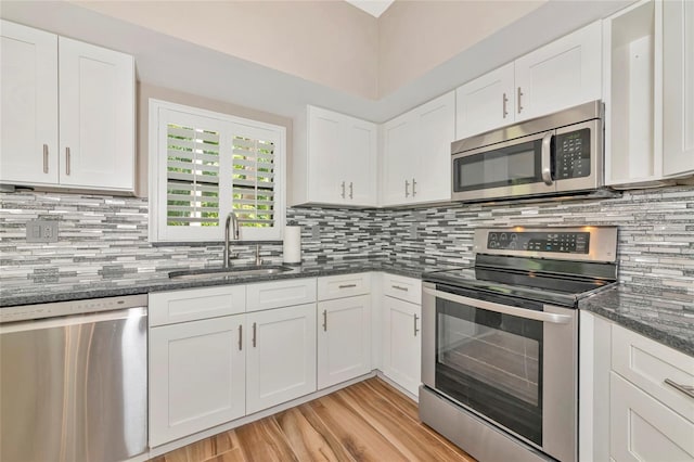 1712 Starling Dr Unit 101, Sarasota, FL 34231 - kitchen featuring stainless steel appliances, white cabinetry, a sink, and light wood-style flooring