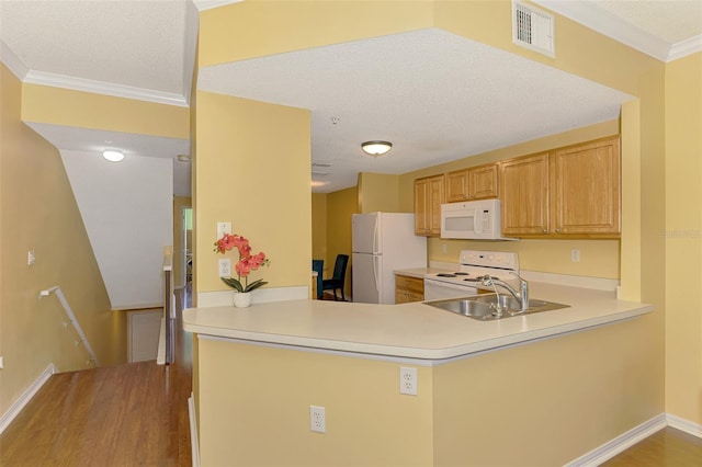 kitchen with visible vents, a sink, white appliances, a peninsula, and light wood-style flooring
