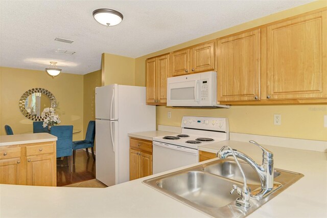 kitchen with light countertops, a textured ceiling, a sink, and white appliances