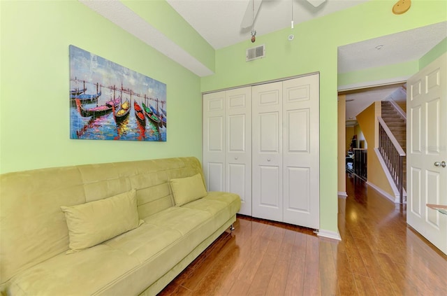 living area featuring stairway, hardwood / wood-style flooring, ceiling fan, baseboards, and visible vents