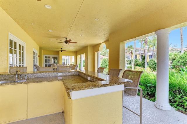 view of patio with ceiling fan, a sink, and outdoor wet bar