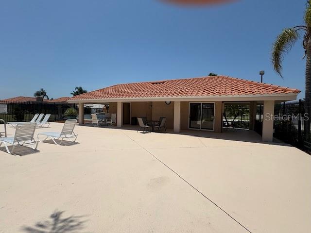 rear view of house featuring a patio area, a tile roof, and fence