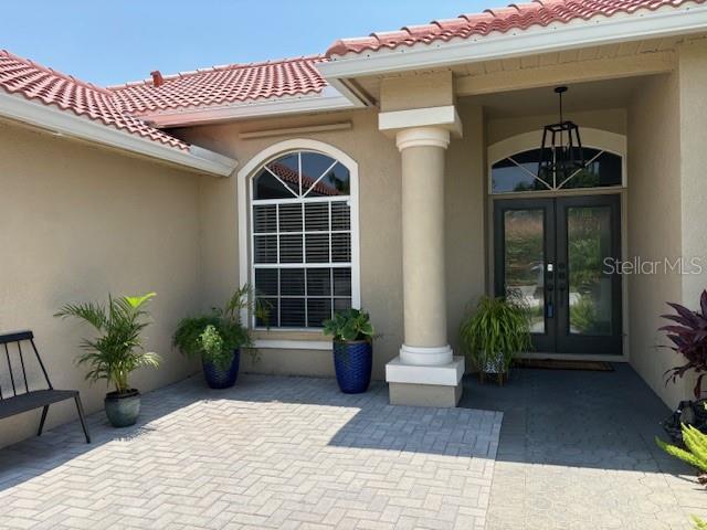 doorway to property featuring stucco siding, french doors, and a tiled roof