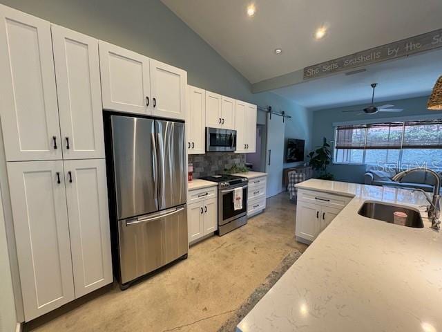 kitchen with a sink, appliances with stainless steel finishes, backsplash, white cabinets, and concrete floors