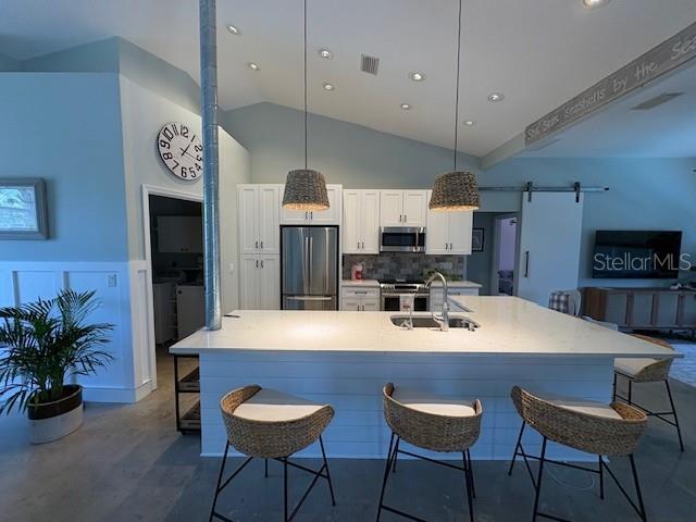 kitchen with visible vents, vaulted ceiling, white cabinetry, backsplash, and appliances with stainless steel finishes