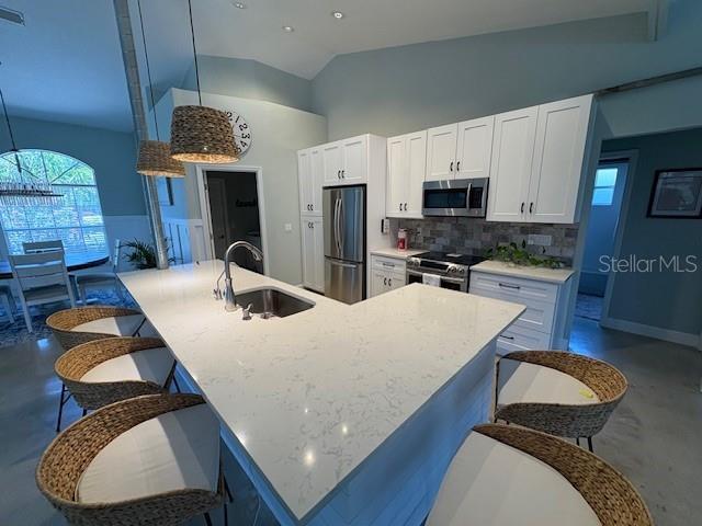 kitchen featuring concrete floors, appliances with stainless steel finishes, a breakfast bar, and a sink