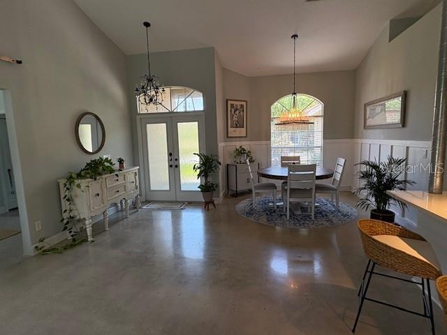 dining area with high vaulted ceiling, an inviting chandelier, and french doors
