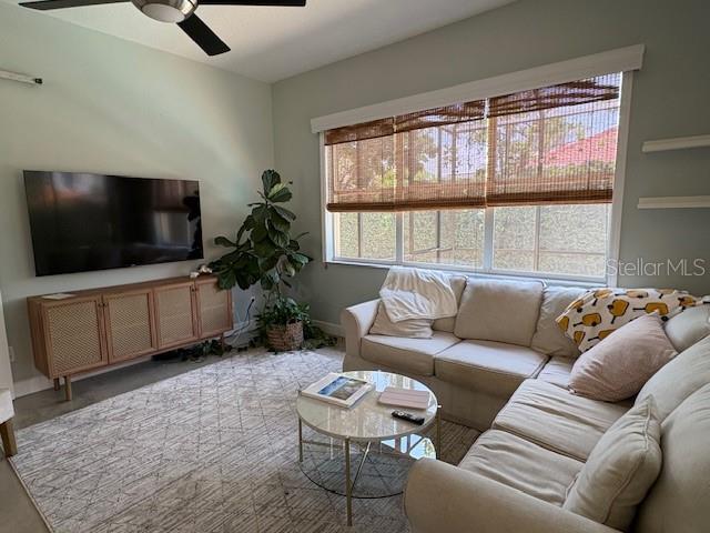 living room featuring baseboards and ceiling fan