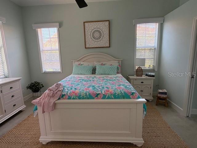 bedroom featuring light carpet, baseboards, and ceiling fan
