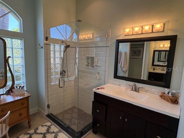 full bath featuring vanity, baseboards, and a stall shower