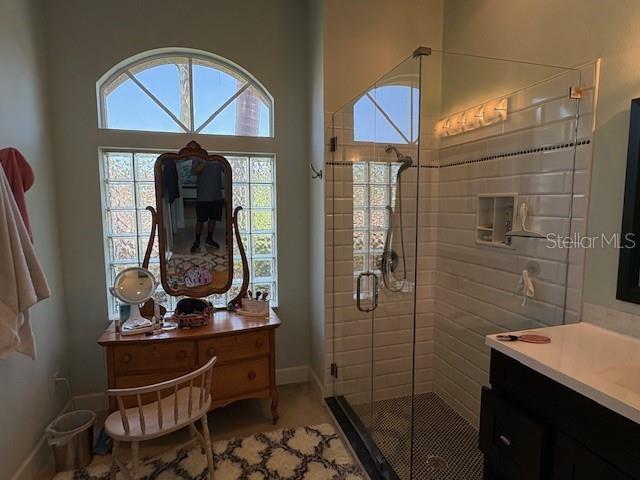 bathroom with vanity, baseboards, and a shower stall