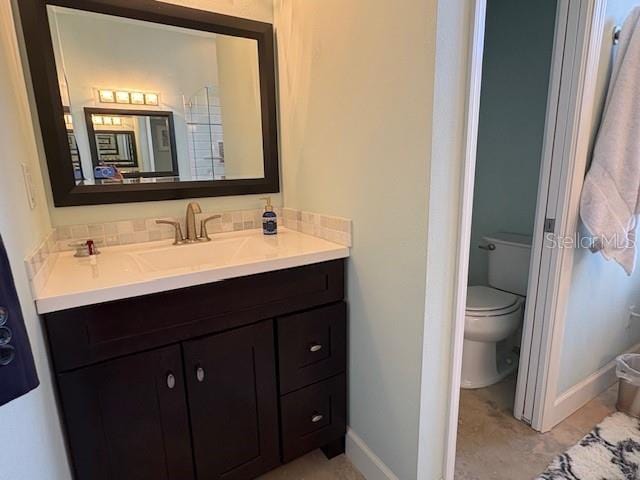 bathroom featuring toilet, baseboards, and vanity