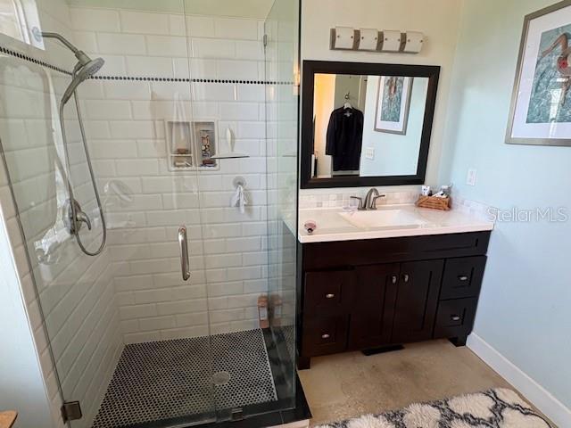 full bath featuring vanity, baseboards, and a shower stall