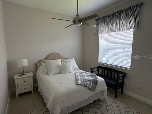 bedroom featuring baseboards, light carpet, and a ceiling fan
