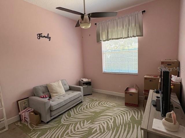 sitting room featuring light carpet, baseboards, and a ceiling fan