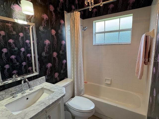 bathroom featuring toilet, shower / tub combo with curtain, and vanity