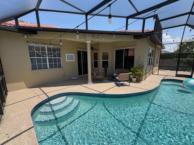view of swimming pool with a patio area, a lanai, and a ceiling fan