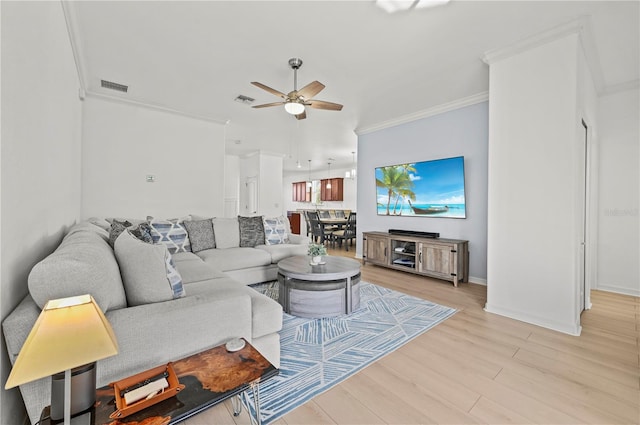 living area featuring light wood-type flooring, ceiling fan, crown molding, and visible vents