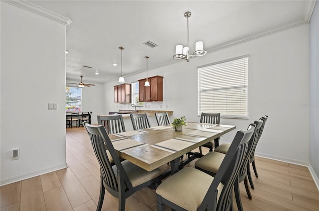 dining space featuring light wood-style flooring, crown molding, a chandelier, and baseboards