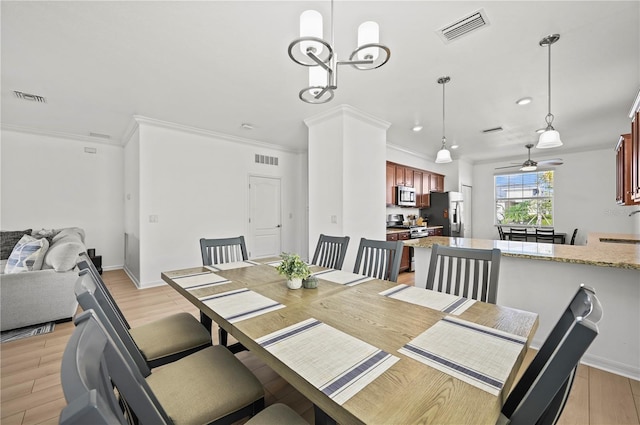 dining space featuring light wood-type flooring, ceiling fan with notable chandelier, and visible vents