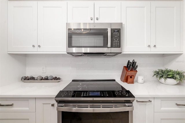 1750 Benjamin Franklin Dr Unit 6B, Sarasota, FL 34236 - kitchen with range with electric stovetop, stainless steel microwave, white cabinetry, and light countertops