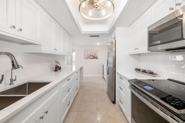 1750 Benjamin Franklin Dr Unit 6B, Sarasota, FL 34236 - kitchen with stainless steel appliances, backsplash, white cabinets, and a tray ceiling