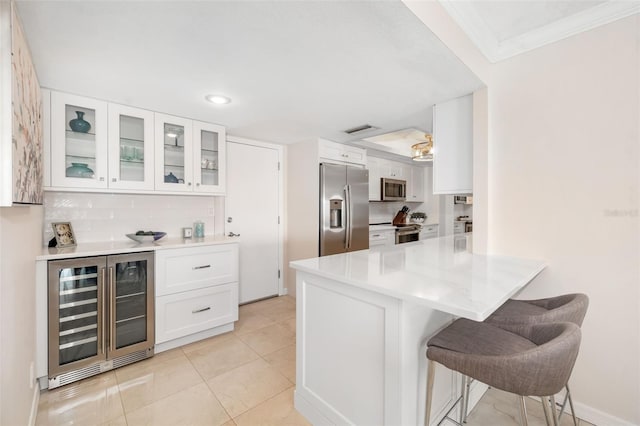 1750 Benjamin Franklin Dr Unit 6B, Sarasota, FL 34236 - kitchen with stainless steel appliances, beverage cooler, a breakfast bar area, a peninsula, and white cabinets