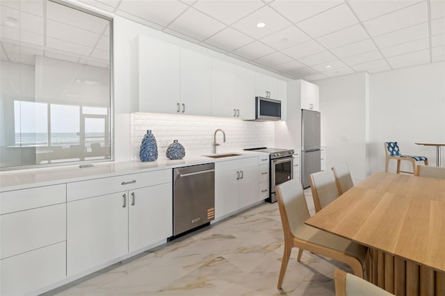 1750 Benjamin Franklin Dr Unit 6B, Sarasota, FL 34236 - kitchen with appliances with stainless steel finishes, a drop ceiling, light marble finish flooring, light countertops, and backsplash