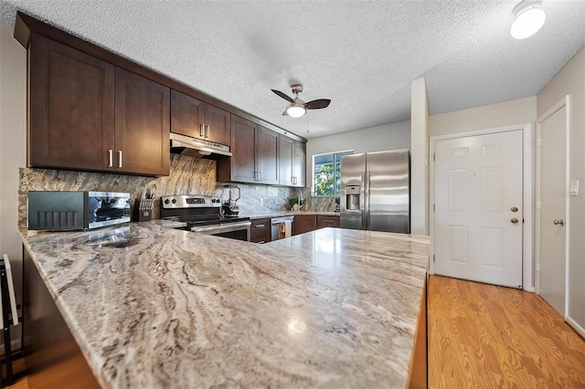 6033 34th St W Unit 132, Bradenton, FL 34210 - kitchen featuring appliances with stainless steel finishes, under cabinet range hood, light wood-style floors, light stone countertops, and a textured ceiling
