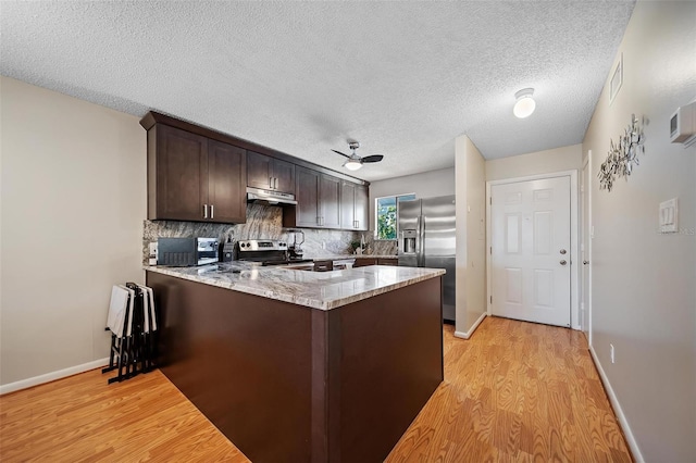 6033 34th St W Unit 132, Bradenton, FL 34210 - kitchen with appliances with stainless steel finishes, a peninsula, light wood-type flooring, dark brown cabinets, and a textured ceiling