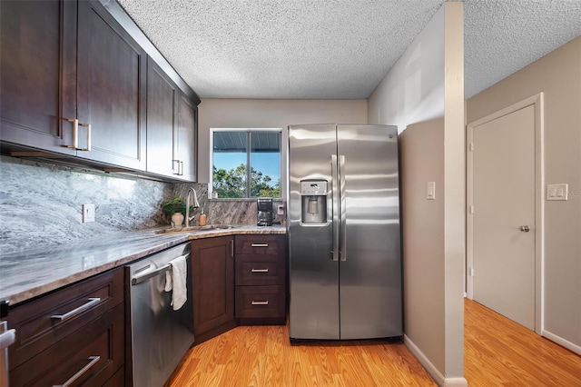 6033 34th St W Unit 132, Bradenton, FL 34210 - kitchen with appliances with stainless steel finishes, a sink, light wood-type flooring, decorative backsplash, and a textured ceiling