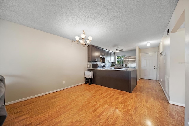 6033 34th St W Unit 132, Bradenton, FL 34210 - kitchen with stainless steel fridge, light wood finished floors, a peninsula, a chandelier, and a textured ceiling